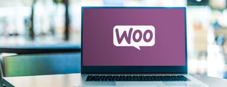 لابتوب مفتوح يعرض شعار WooCommerce على خلفية أرجوانية – تمثيل لمنصة التجارة الإلكترونية الشهيرة
